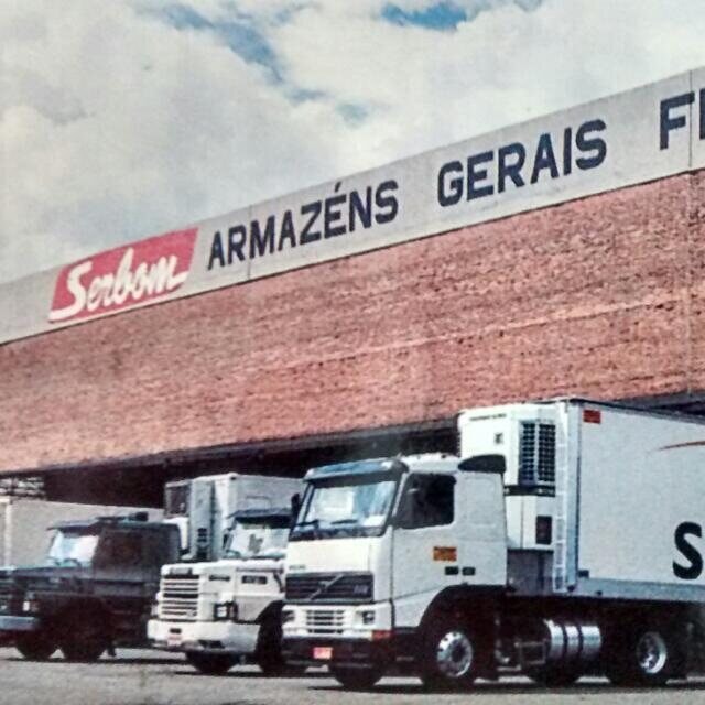 Foto histórica do armazém da SERBOM Armazéns Gerais Frigoríficos, com caminhões baú estacionados na plataforma