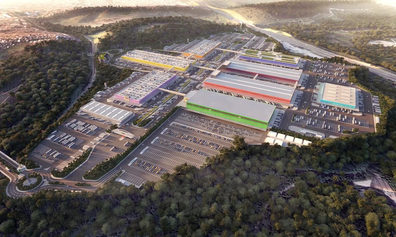 Render tridimensional do NESP visto de cima: galpões alinhados em torno de pátios de manobra, cercados por mata, com a rodovia à direita